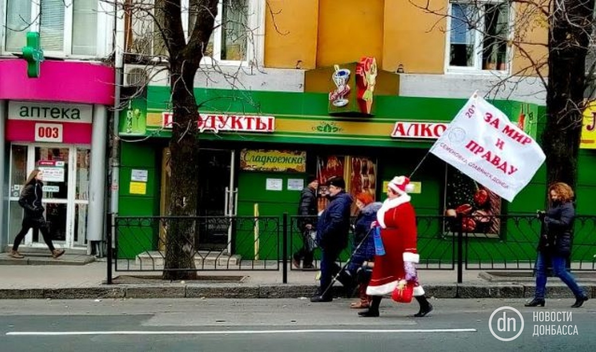 Активистка «ДНР» и волонтер с позывным «Дед Мороз» идет с флагом по проспекту Гурова

