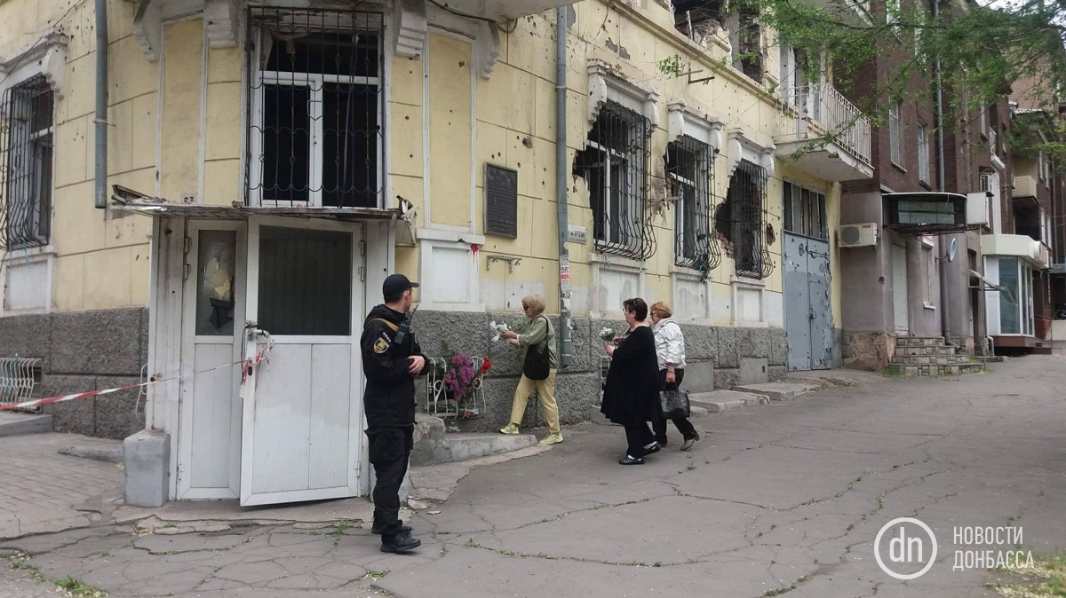 Жители Мариуполя несут цветы к сгоревшему зданию милиции