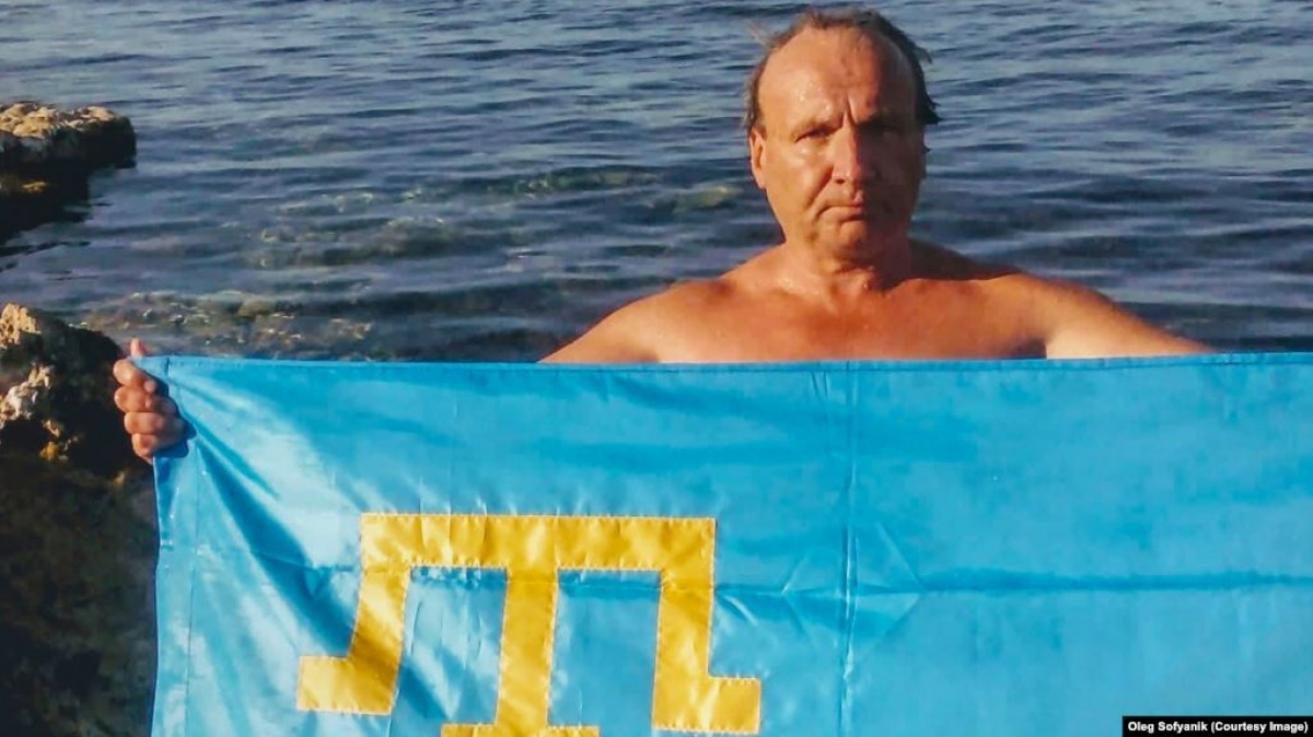 Олег Софяник держит флаг крымских татар