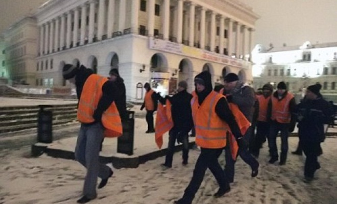 Люди в гражданском одевают форму работников ШЕДа: оранжевые накидки поверх кожаных курток