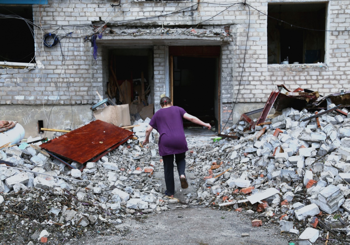 Жінка біжить у квартиру повз руїни багатоповерхівки у Часовому Яру, липень 2022. Фото: Вікторія Рощина / Новини Донбасу
