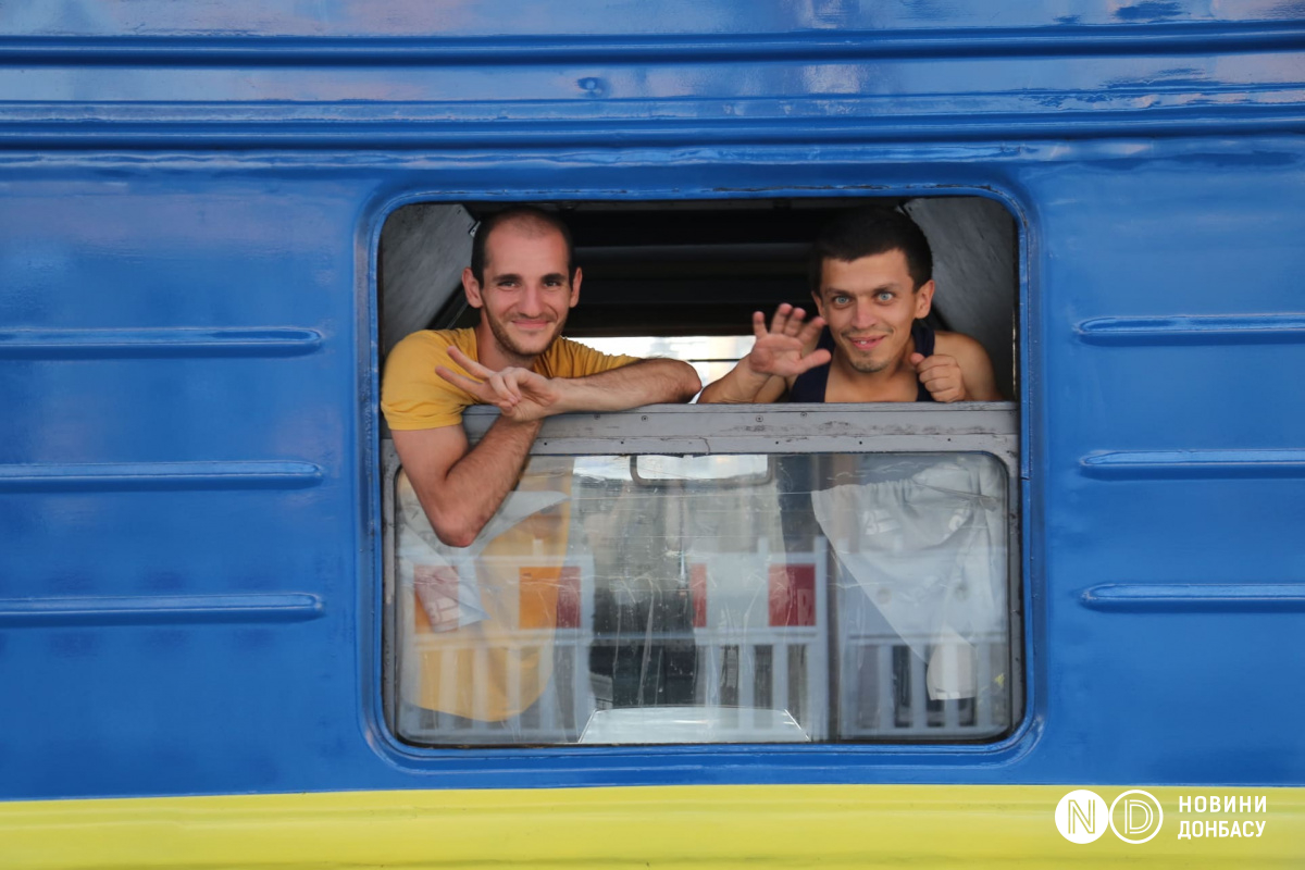 Мужчины смотрят в окно эвакуационного поезда, июль 2022. Фото: Виктория Рощина / Новости Донбасса