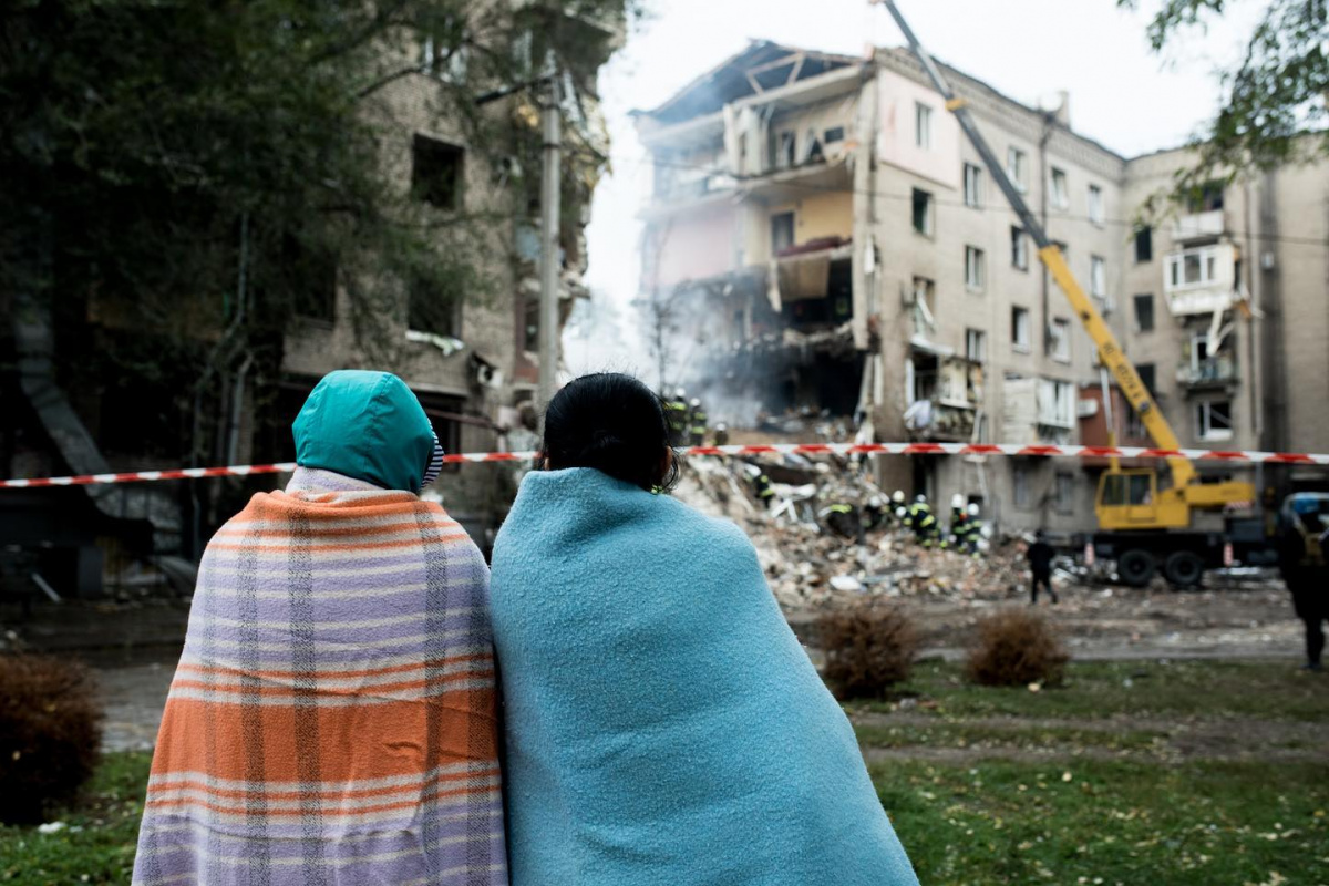 Люди перед зруйнованим внаслідок російських обстрілів будинком у Запоріжжі. Фото: Олена Тіта