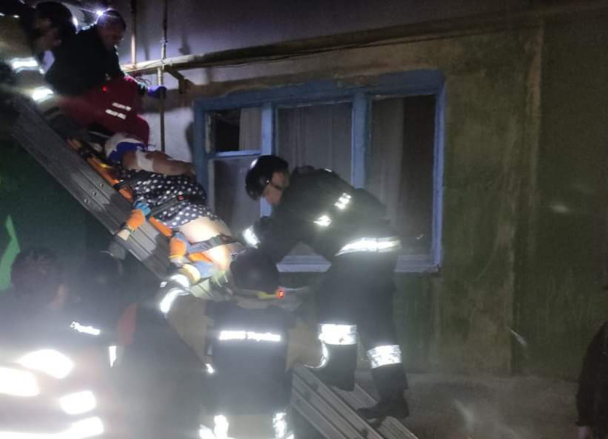 Рятувальники знімають жінку, що випала з вікна, з козирка під'їзду в Костянтинівці Донецької області. Фото: ДСНС